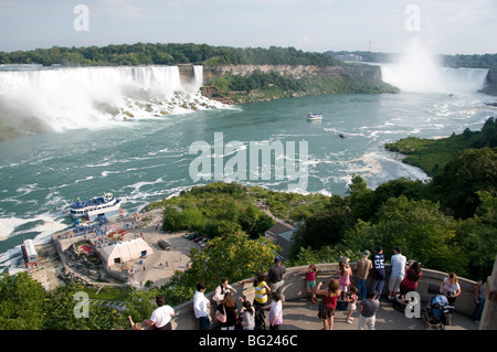 Touristen genießen den Blick auf die Niagarafälle. Die amerikanischen Wasserfälle sind auf der linken Seite, die Horseshoe Falls auf der rechten Seite. Stockfoto