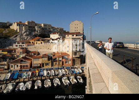 Fischerboote und -Häuser im Hafen von Vallon des Auffes Inlet, Brücke über die Corniche, & Joggers, Marseille oder Marseille, Provence, Frankreich Stockfoto