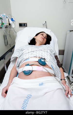 Kaukasische Hispanic Latina schwangeren Verlegung in einem Krankenhausbett Gurney in der Triage-Einheit einen medizinische nicht Stress-Test zu tun. Stockfoto