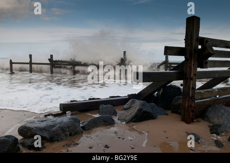 Wellen schlagen einen Wellenbrecher auf Norfolk Küste bei Happisburgh Stockfoto