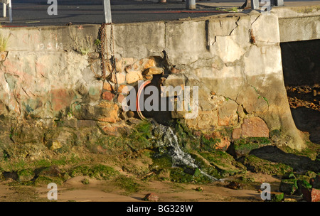 Dieses alte Abflussrohr in der Seite der Steg wurde ausgesetzt, wenn die Flut von der Bucht in Simons Town Hafen, Kapstadt ging. Stockfoto