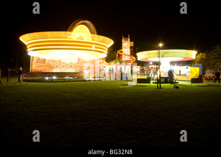 Riesenrad und Karussell beleuchtet in der Nacht auf einer Kirmes in Chesterfield Derbyshire East Midlands England Stockfoto