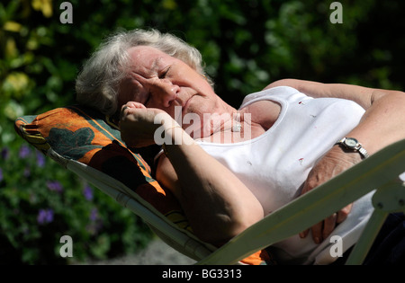 ÄLTERE DAME SCHLAFEN BEI SONNIGEM WETTER IN IHREM GARTEN Stockfoto