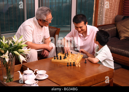 Junge spielt Schach mit seinem Vater und Großvater zu Hause Stockfoto