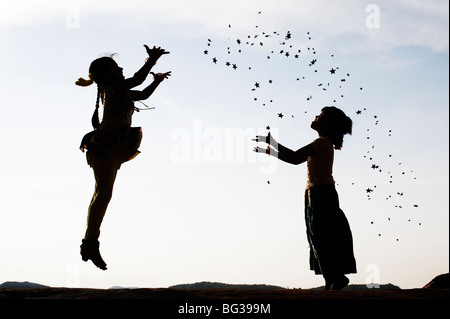 Silhouette von zwei jungen indischen Mädchen springen, werfen und fangen Sternen. Indien Stockfoto