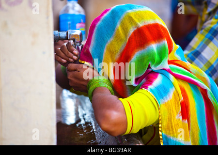 Verschleierte Frau aus einem Wasserhahn trinken, während das Kamel-Mela in Indien Pushkar Stockfoto