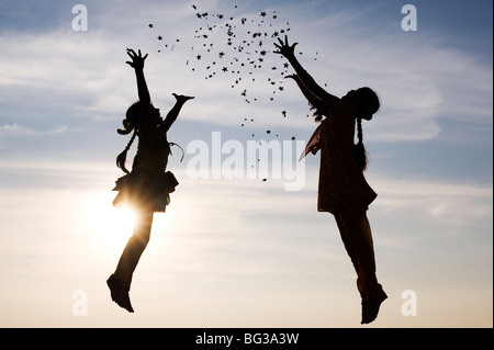 Silhouette von zwei jungen indischen Mädchen springen, werfen und fangen Sternen. Indien Stockfoto