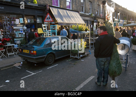 ein Mann, der einen Weihnachtsbaum an Columbia Road Flower Market in London gekauft hat Stockfoto