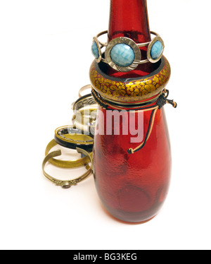 eine Auswahl an preiswerten und fröhlich Armbänder und Armreifen - einige platziert um den Hals eine rote Flasche - auf einem weißen Hintergrund. Stockfoto