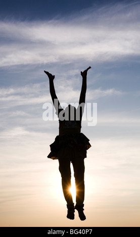 Silhouette eines indischen Mädchens bei Sonnenuntergang in die Luft springen. Indien Stockfoto