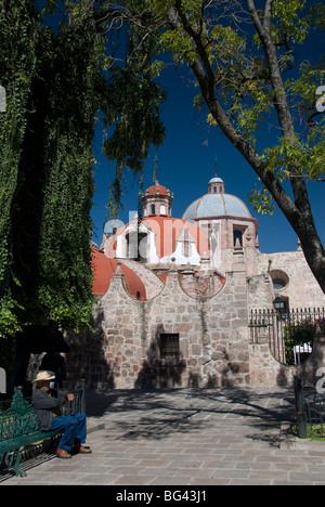 Lokale Mann ruht auf einer Parkbank mit Iglesia del Carmen im Hintergrund, Morelia, Michoacan, Mexiko, Nordamerika Stockfoto