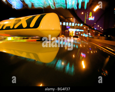 Nahaufnahme von Taxischild auf Autodach mit Neon Straße Zeichen, Shanghai, China, Asien Stockfoto