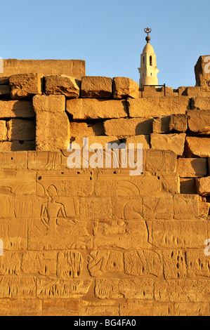 Schnitzereien an der Wand der Hof von Ramses II mit Minarett der Moschee von Abu el-Haggag im Hintergrund, Luxor-Tempel, Ägypten Stockfoto