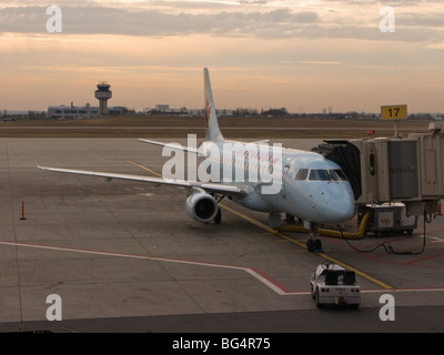 Eine Embraer 190 von Air Canada durchgeführten sitzt an einem Tor an der Ottawa International Airport bei Sonnenuntergang. Stockfoto