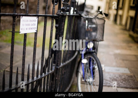 Fahrräder, angekettet an einen Zaun mit Warnzeichen, dass sie in der Universitätsstadt Cambridge in England entfernt werden Stockfoto