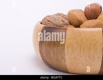 Holzschale mit gemischten Nüssen in ihren Schalen, Haselnüsse, Walnüsse und Mandeln gefüllt. Stockfoto