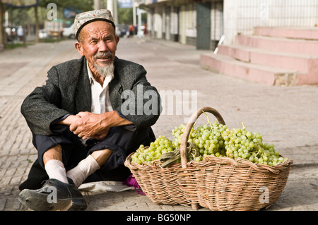 Ein Alter Mann in uigurischen Verkauf von Trauben in der alten Stadt Kashgar. Stockfoto