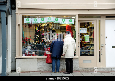 Paar schauen im Fenster des Oxfam Shop kurz vor Weihnachten Highgate Village London England Großbritannien Stockfoto