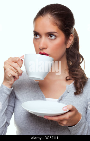 Ein Frau trinken Tee aus einer Tasse und Untertasse wie denkt über etwas, weißer Hintergrund. Stockfoto