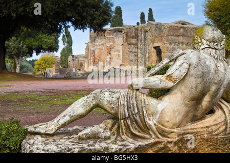 Ein Blick über eine Statue in der Nähe von Canopus in Richtung der großen Bäder Hadrians Villa. Zwei Touristen finden Sie ein Zeichen in der Ferne. Stockfoto