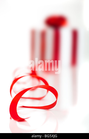 Geschenk verpackt mit einem roten Band auf weißem Hintergrund, Fokus liegt dabei auf der Multifunktionsleiste Stockfoto