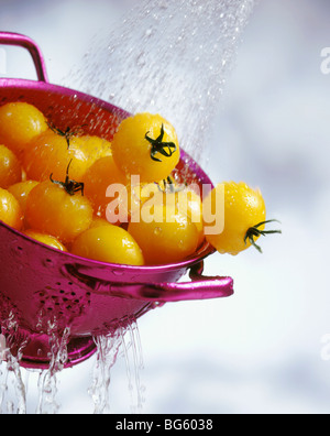 Gelbe Cherry-Tomaten waschen in Sieb mit Wasser Stockfoto