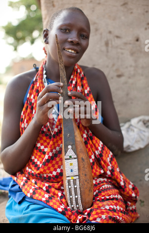 Eine Massai-Frau in traditioneller Kleidung hält ein Milchkännchen, geschmückt mit Perlen in Kilombero Dorf, Manyara Region, Tansania. Stockfoto