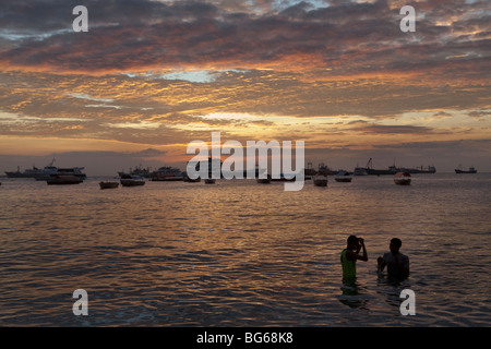 Jugendliche Schwimmen bei Sonnenuntergang den Zanzibar-Hafen in Stonetown. Stockfoto