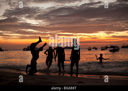 Jugendliche spielen bei Sonnenuntergang an der Küste des Indischen Ozeans in Stonetown, Sansibar, Tansania. Stockfoto