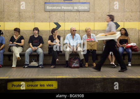 Ein Mitarbeiter der Zustelldienste führt Passagiere auf dem unterirdischen Bahnsteig Passeig de Gracia Barcelona Katalonien Spanien Stockfoto