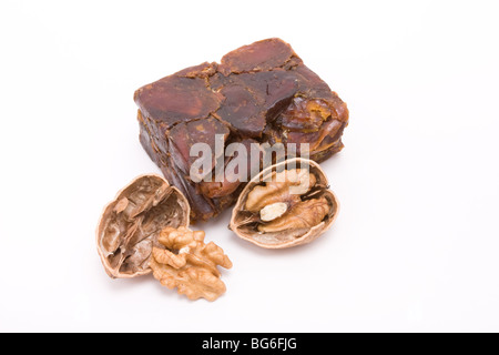 Block von gepressten, getrocknete Datteln mit gerissenen Walnuß-Hälften auf weißen Hintergrund isoliert zu öffnen. Stockfoto