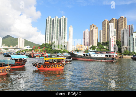 Drei Sampans rückwärts in die Fluten des Aberdeen Harbour, ein Hochhaus mit Angeln Boot Kulisse, Hong Kong, China Stockfoto