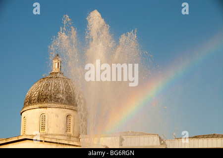 Ein Regenbogen in der Gischt des einer der Brunnen am Trafalgar Square in London, Vereinigtes Königreich. Stockfoto