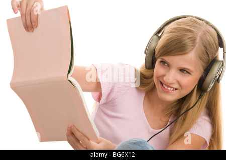 Teenager-Mädchen mit Buch Musikhören isoliert auf weißem Hintergrund Stockfoto