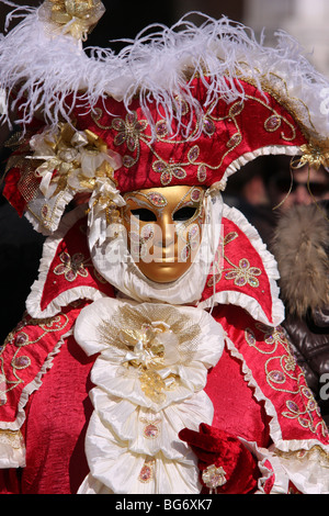 Nahaufnahme eines venezianischen Mann oder Frau trägt eine goldene Maske und einem roten und weißen bestickten Kostüm in Venedig Karneval 2009 Stockfoto