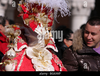 Nahaufnahme eines venezianischen Mann oder Frau trägt eine goldene Maske und einem roten und weißen bestickten Kostüm in Venedig Karneval 2009 Stockfoto