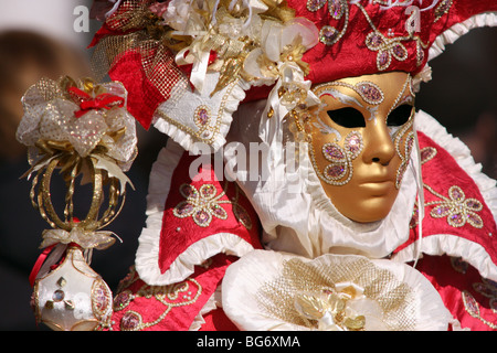 Nahaufnahme eines venezianischen Mann oder Frau trägt eine goldene Maske und einem roten und weißen bestickten Kostüm in Venedig Karneval 2009 Stockfoto