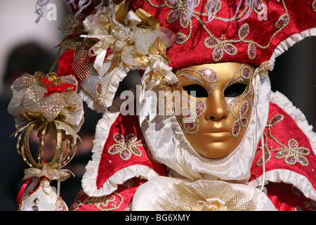 Nahaufnahme eines venezianischen Mann oder Frau trägt eine goldene Maske und einem roten und weißen bestickten Kostüm in Venedig Karneval 2009 Stockfoto