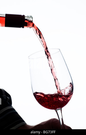 Rotwein ins Weinglas aus Flasche gegossen wird Stockfoto