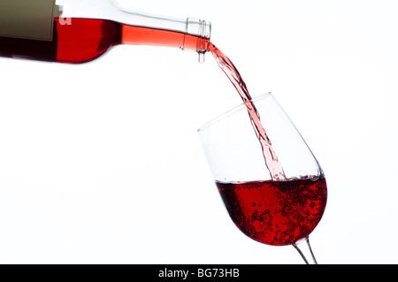 Rotwein ins Weinglas aus Flasche gegossen wird Stockfoto