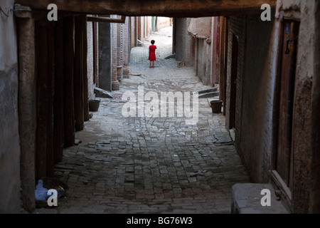 Ein kleines Mädchen in einer alten Gasse in der alten Stadt Kashgar, Provinz Xinjiang, China Stockfoto