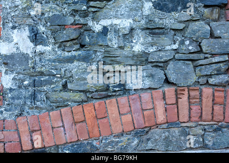 Eine Reihe von roten Bett Ziegel durchzieht ein altes steinernes Gebäude in Cornwall. Stockfoto