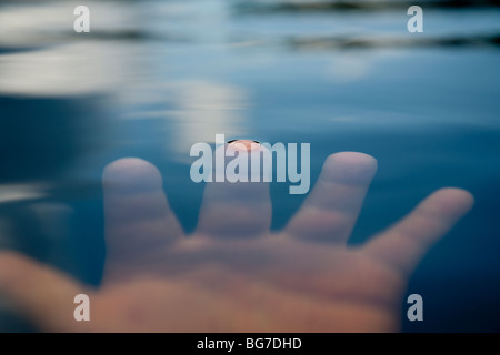 Ein Finger erreicht kaum die Oberfläche von unter Wasser Stockfoto