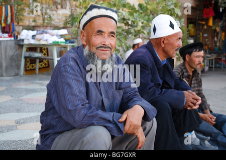 Uyghur bedeuten sitzen auf dem Hauptplatz der Altstadt von Kashgar, Provinz Xinjiang, China Stockfoto