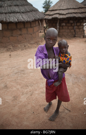 Ein Junge trägt ein kleines Kind in Acowa Flüchtlingslager in Amuria District, Uganda, Ostafrika. Stockfoto