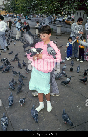 Ein junges Mädchen spielt mit den Tauben am Trafalgar Square in London, England Stockfoto