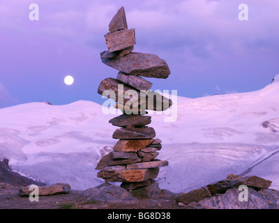 Schweiz, Wallis, Zermatt, Gornergrat, ein Cairn der ausgewogenen Felsen mit einem Mondaufgang und Bergen im Hintergrund Stockfoto