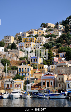 Yachten und Boote vor bunten traditionellen Häuser in Symi Hafen, Insel Symi, Griechenland Stockfoto