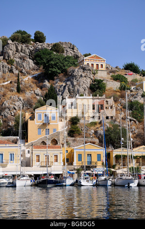 Yachten und Boote vor bunten traditionellen Häuser in Symi Hafen, Insel Symi, Griechenland Stockfoto