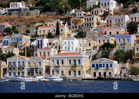 Yachten und Boote vor bunten traditionellen Häuser in Symi Hafen, Insel Symi, Griechenland Stockfoto